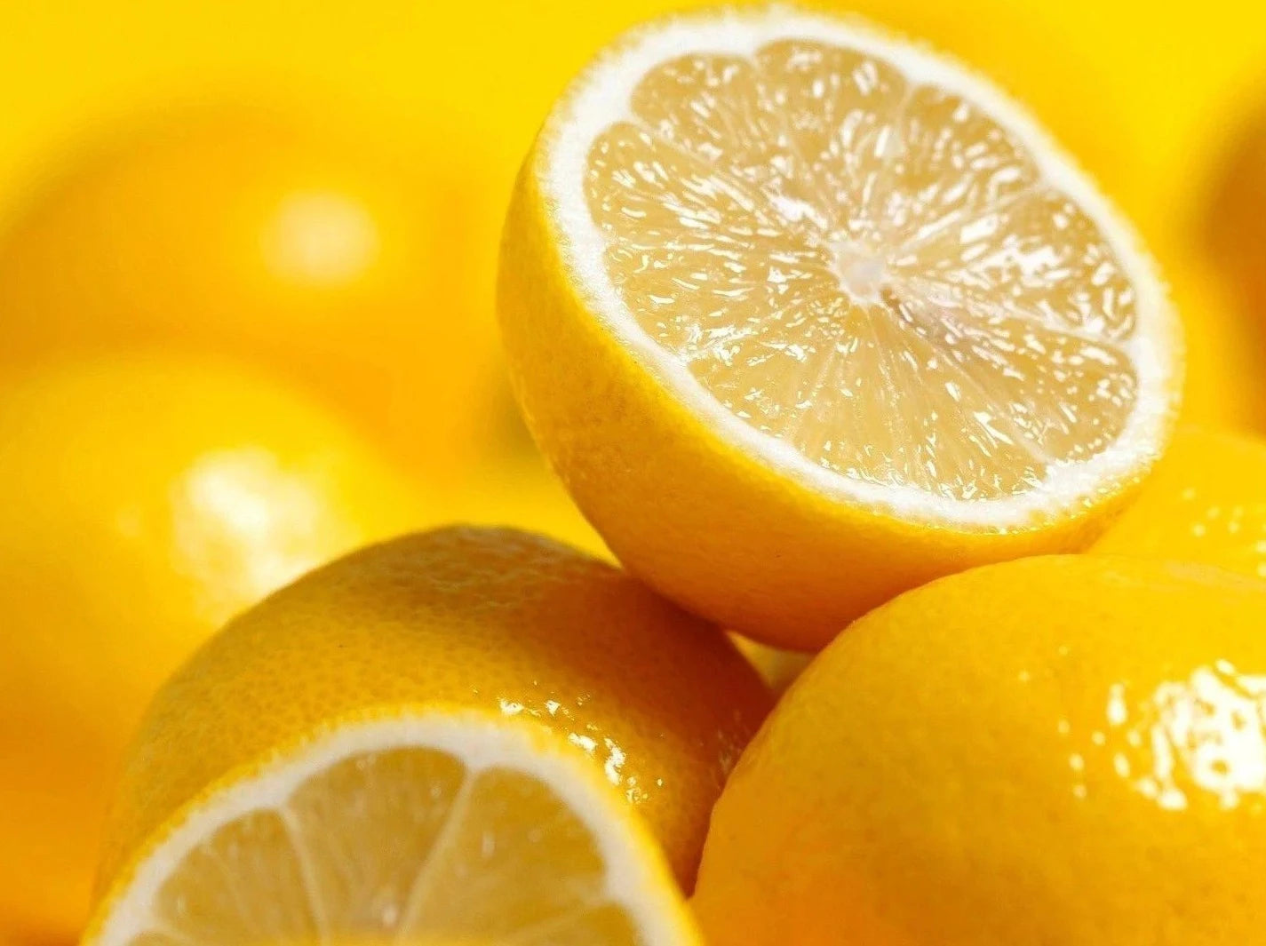 Bright yellow Lemons, some cut in half showing off the juicy centre.