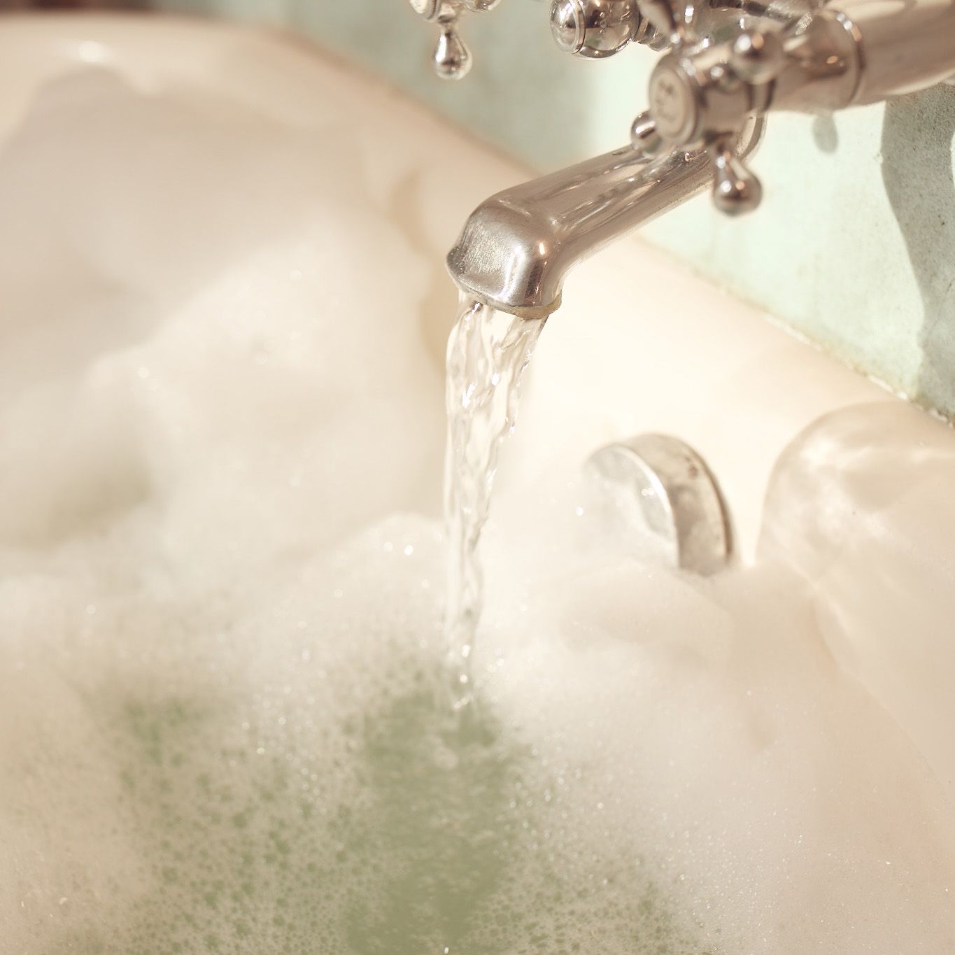 A fancy tap pouring water into a relaxing bubble bath.