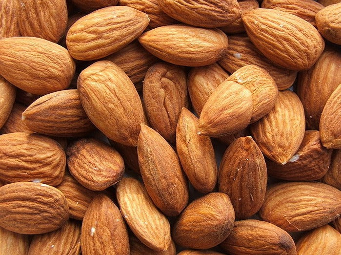 Sweet almonds piled on top of each other as an example of what gets turned into sweet almond oil