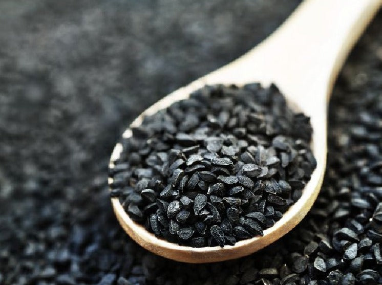 Black cumin seeds on a wooden spoon.